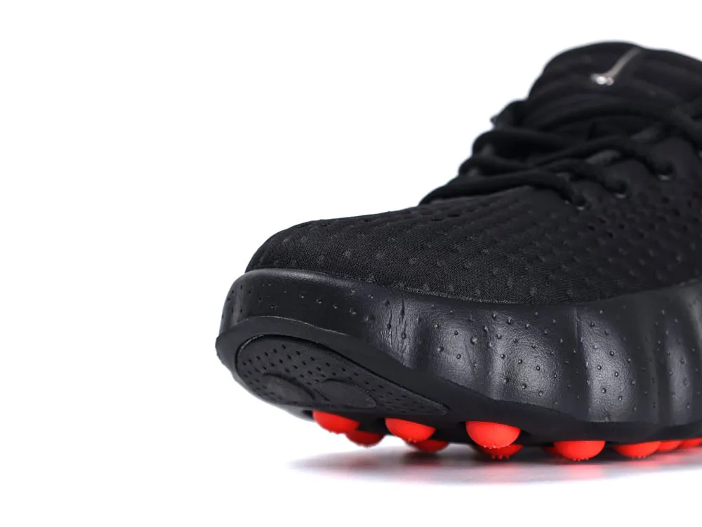 Black mesh sneaker with rubber sole featuring red traction points.