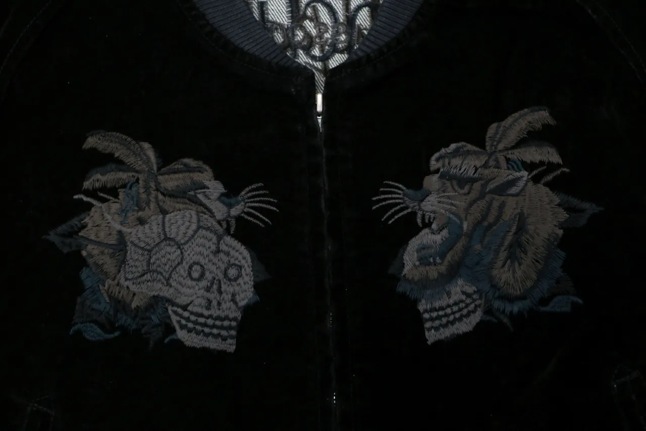 Black velvet jacket with embroidered animal designs near the collar and zipper.