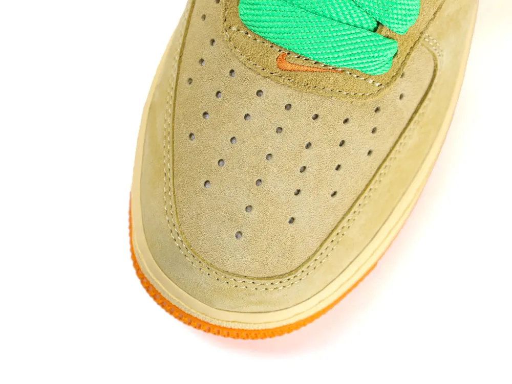 Close-up of a tan suede sneaker with green laces and orange accents.