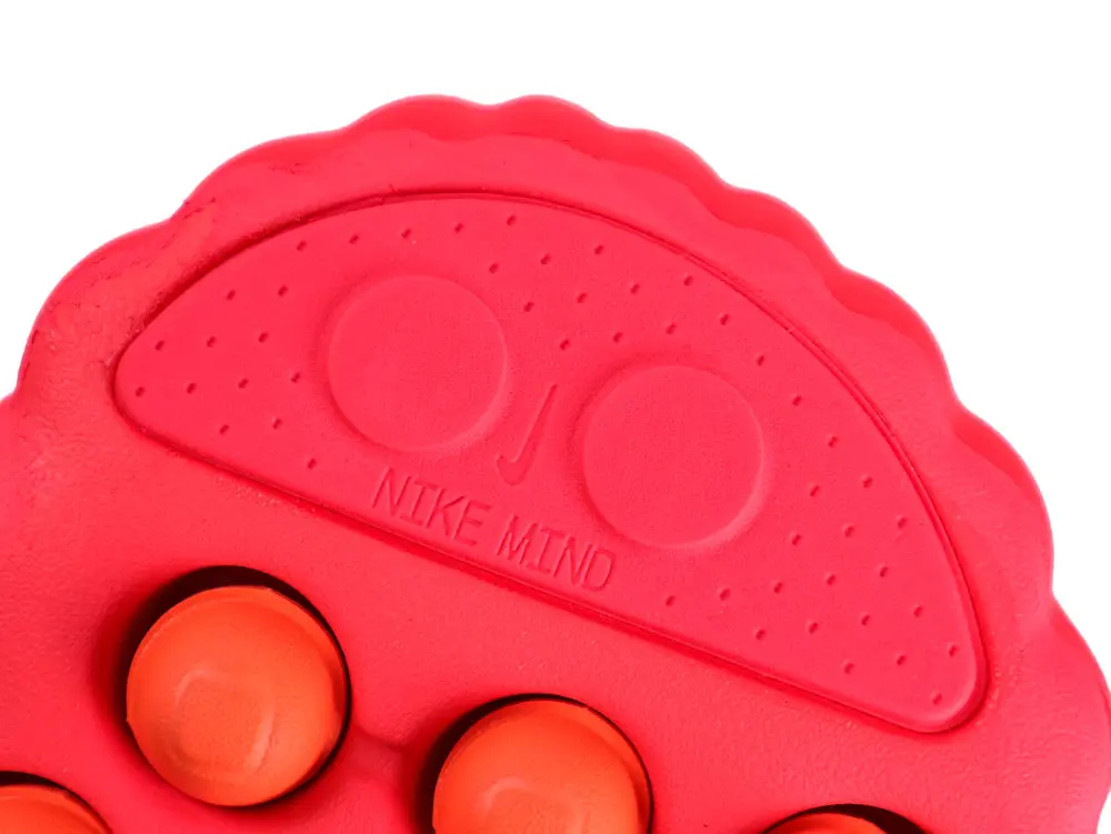 Red rubber component with textured surface and circular orange accents.