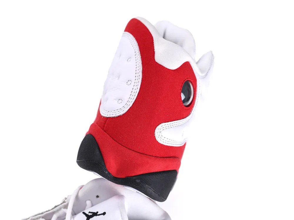 Close-up of red, white, and black sneaker upper with suede material and eyelet.