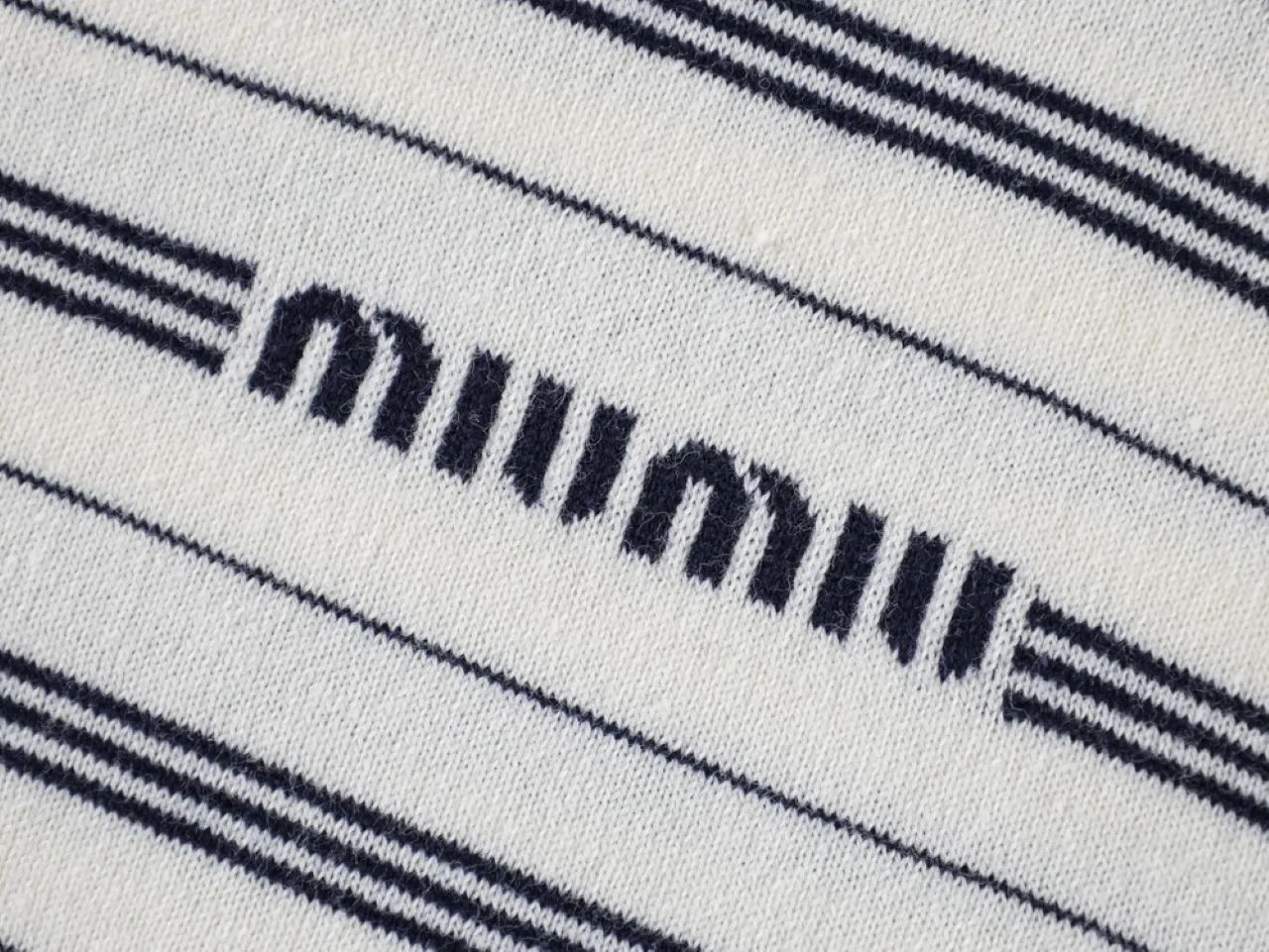 White and black striped wool fabric with logo detail in the center.