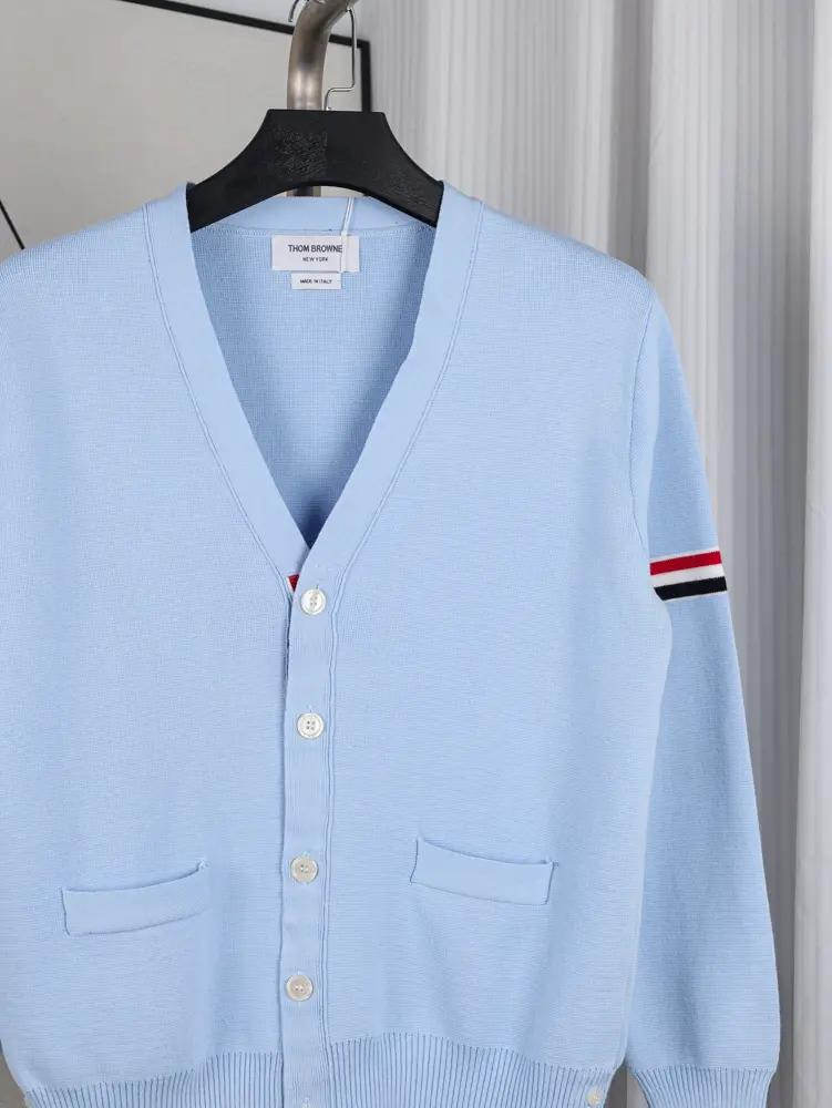 A front view of the chest area of the Fine Merino Wool RWB Armband Cardigan in sky blue, showcasing its deep navy merino wool material and the neck label
