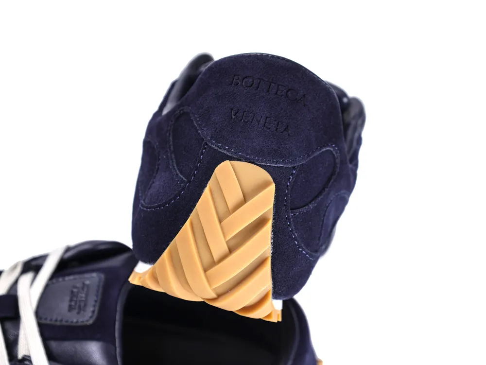Navy suede and rubber sneaker heel with embossed text and beige sole detail.