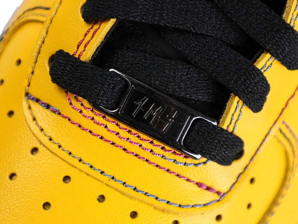 Yellow leather shoe with black laces and metal lace tag holder.