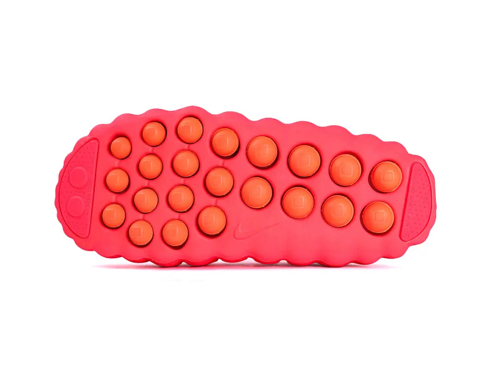 Red and orange rubber sneaker sole with circular cushioning elements.