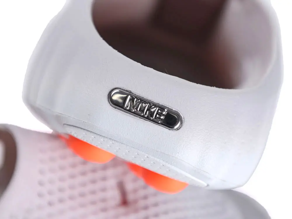 White synthetic shoe heel with metallic logo and orange cushion accents.