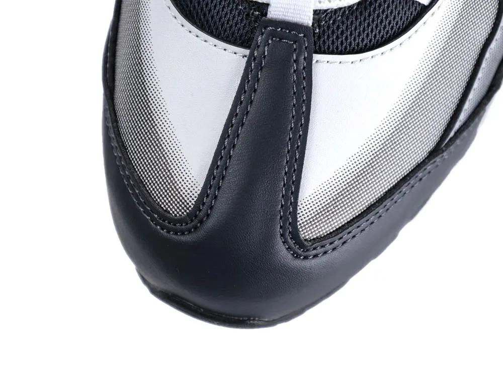 Close-up of a black and white leather sneaker toe with mesh accents.
