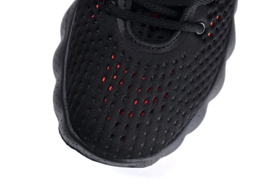Black perforated fabric sneaker upper with red accents and black laces.