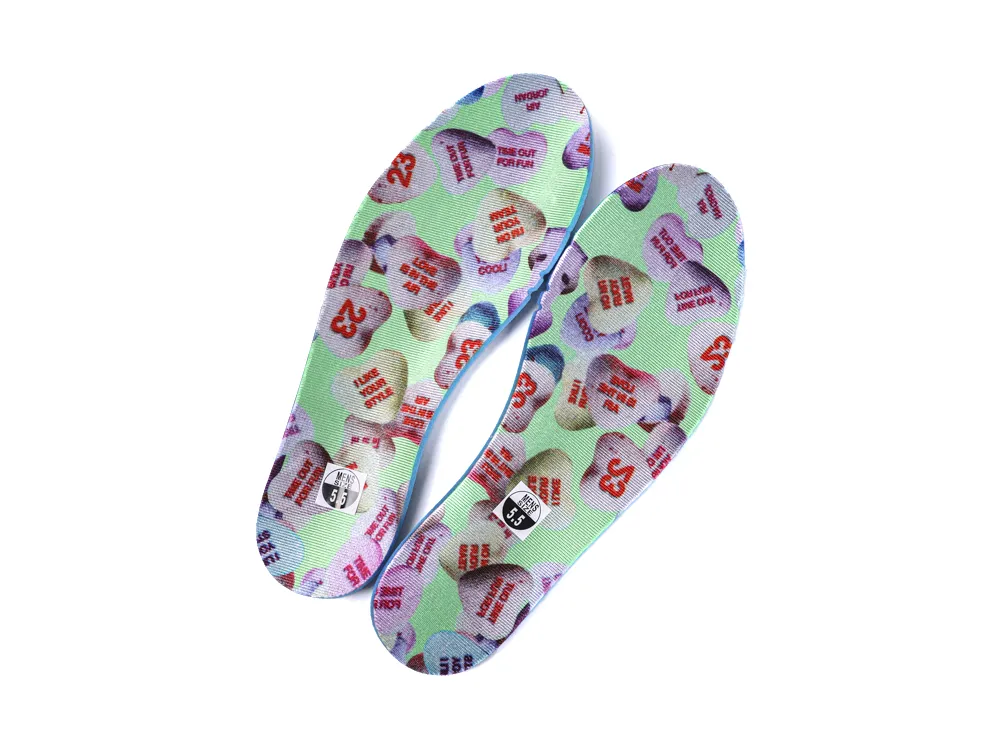 Pair of sneaker insoles featuring a mint green background and colorful conversation heart candy patterns.