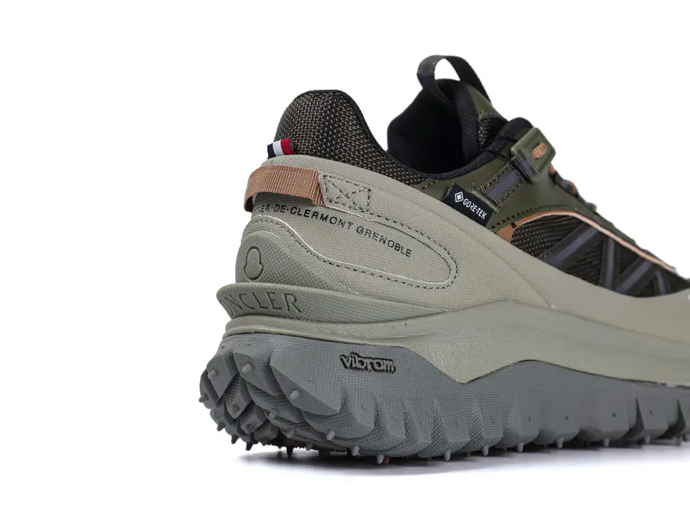 Close-up of a sneaker showing textured green and gray materials, angular design, and rugged gray sole with distinct tread.