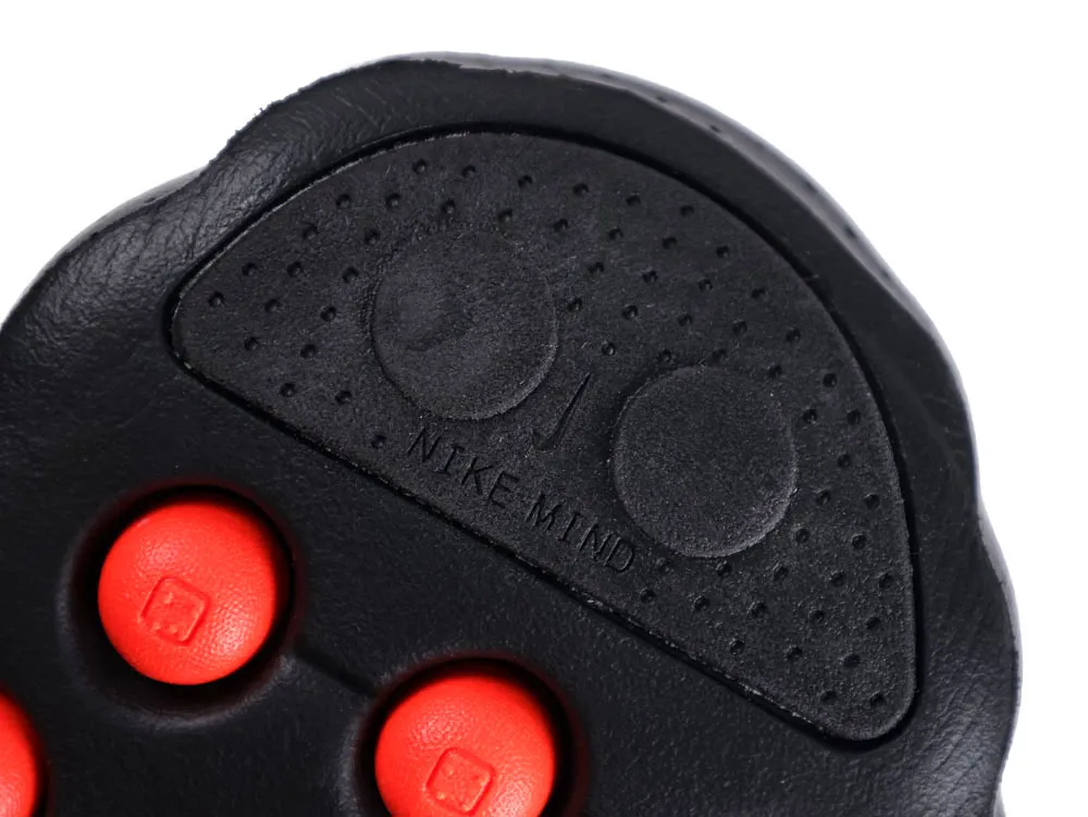 Close-up of a black rubber shoe sole with red accents and textured surface.