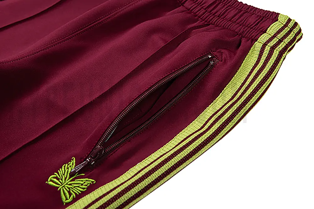 Close-up detail of the track pants pocket and delicate butterfly embroidery.