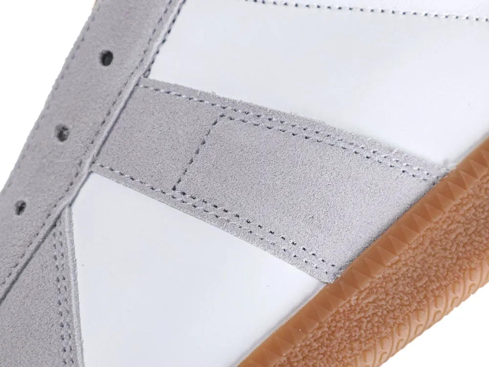 Close-up of a white and gray suede sneaker with brown rubber sole.