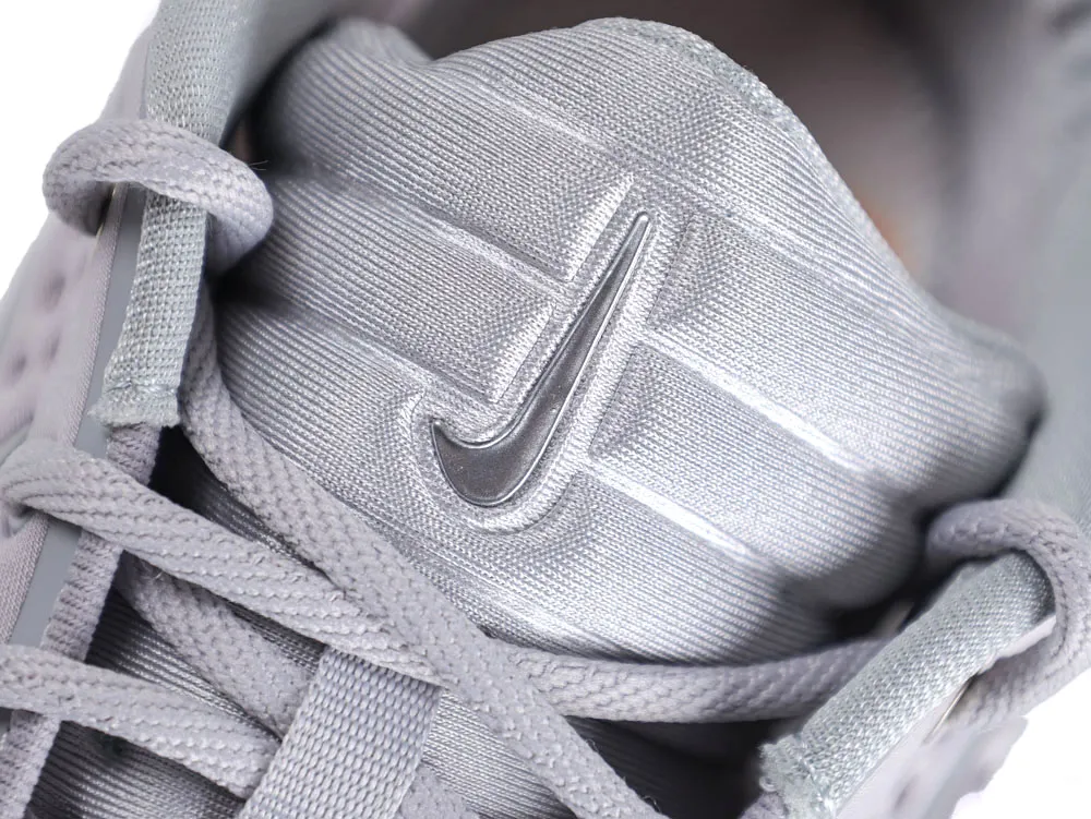 Close-up of silver fabric shoe tongue with laces and logo detail.