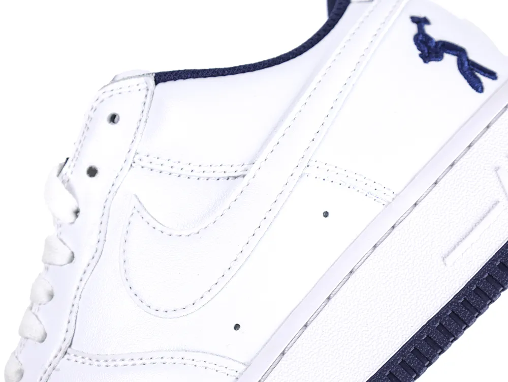 White leather sneaker with a dark blue logo and matching outsole detail.